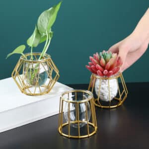 Vase miniature comprenant une petite vasque en verre supportée par une armature en métal doré de forme géométrique. Idéal pour les petites fleurs ou les plantes grasses.
