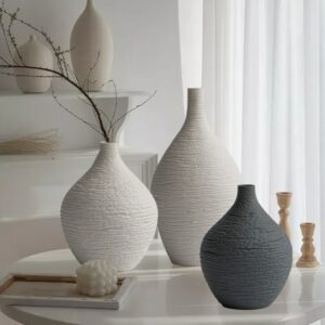 Plusieurs vases soliflores de tailles variées, de forme ronde, en gris et blanc.