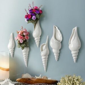 Vase coquillage suspendu blanc, en céramique. Il est disponible en plusieurs tailles et s'accroche aux murs.