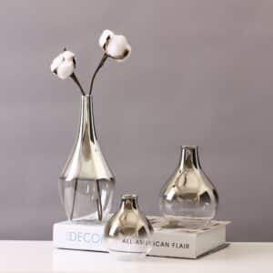 Vase en verre transparent teinté par un dégradé de couleur argenté. Il est disponible dans des formes variées de petites bouteilles. Son petit format lui permet d'accueillir des soliflores ou des petits bouquets.