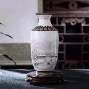 Ce vase chinois ancien est fabriqué en céramique. Il est blanc et agrémenté de motif, comme ce paysage sous la neige, typique de l'art pictural chinois. Le col du vase est également travaillé avec des ornements traditionnels.
