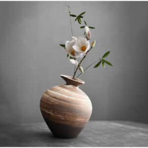 Ce vase japonais est un petit soliflore en porcelaine. Sa forme de petite amphore en boule lui donne un style unique. Il est émaillé et peint en marront et blanc.