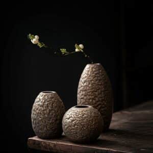 Petit vase japonais doré en céramique. De forme ronde et ovale, sa texture imite celle des matériaux chauffés au four à céramique. La teinte du vase est couleur bronze avec des reflets dorés. C'est un soliflore caractéristique du style épuré japonais.