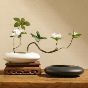 Vase japonais plat en forme de galet rond, disponible en noir et blanc. Il arbore les caractéristiques typiques d'un vase soliflore japonais dans l'esprit zen.
