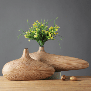 Vase japonais en bois rayé, fabriqué à partir d'un seul bloc. Il est de forme ovale, tout en largeur. Il a un style moderne et original. Il intègre un bouquet de fleurs jaunes.