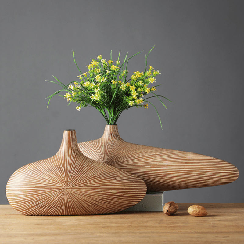 Vase japonais en bois rayé, fabriqué à partir d'un seul bloc. Il est de forme ovale, tout en largeur. Il a un style moderne et original. Il intègre un bouquet de fleurs jaunes.