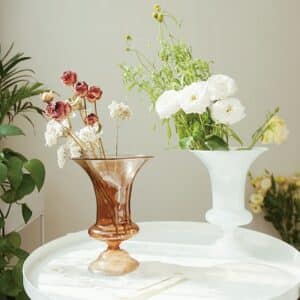 Vase en verre dans l'esprit Médicis, avec cette forme évasée caractéristique. Disponible notamment en blanc et marron, son aspect transparent amène une certaine modernité à ce style antique.