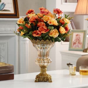 Ce vase d'exception est inspiré de la forme mythique des vases Médicis. Son corps en verre est positionné sur un pied en métal doré. Il est également orné de dorures sur le pourtour de son col. Il contient un bouquet de roses multicolores.