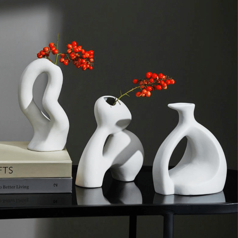 Petit vase décoratif minimaliste en céramique blanche. C'est un style de vase original, avec des formes abstraites, d'inspiration scandinave. C'est un vase soliflore garnit d'un joli brin de plante à fruits rouges.