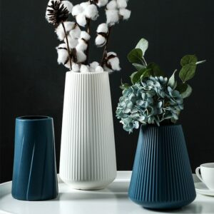Vase décoratif en plastique incassable de style moderne. Le vase est de forme tubulaire, avec des striures sur le pourtour. Il est disponible en bleu, blanc et rose.