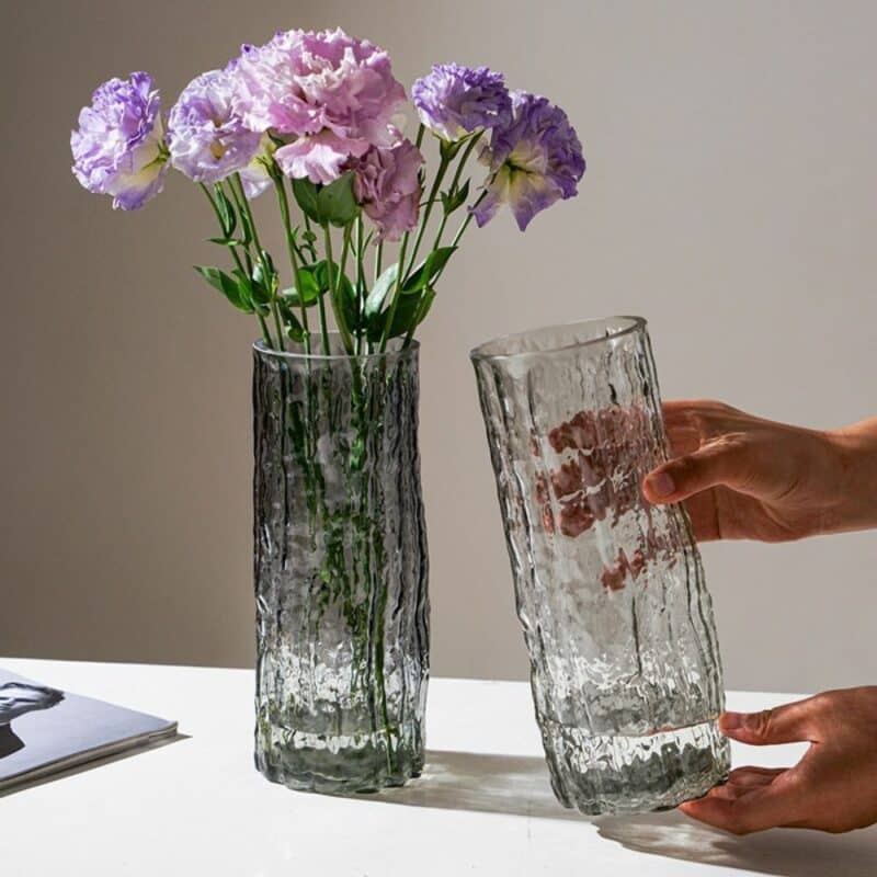 Deux vases décoratifs d'inspiration moderne. Ils ont de style Murano. Fabriqués en verre, ils sont soufflés à la main et sculpté pour obtenir une surface de texture irrégulière. Un des vases est noir, il contient des fleurs mauves, l'autre est transparent.