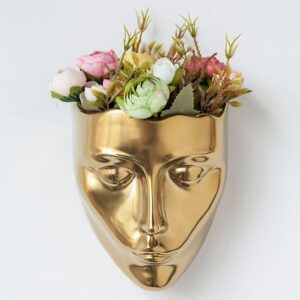 Vase doré suspendu en forme de visage. Sa peinture brillante apporte de la luminosité dans votre décoration intérieure. Fleurissez votre intérieur d'une manière originale avec ce vase unique. Vous pouvez le garnir d'un bouquet de fleurs ou d'une plante colorée.