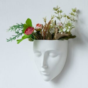 Vase blanc suspendu en forme de visage. Sa peinture brillante apporte de la luminosité dans votre décoration intérieure. Fleurissez votre intérieur d'une manière originale avec ce vase unique. Vous pouvez le garnir d'un bouquet de fleurs ou d'une plante colorée.