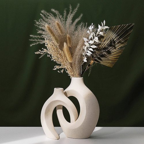 Vase double ajouré en céramique beige. Il est doté d'un design original inspiré du style scandinave. Il contient un bouquet de fleurs séchées de type pampa.